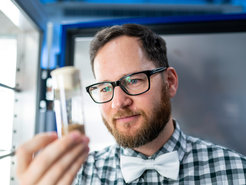Ian Keesey looks at a container of fruit flies in the laboratory.